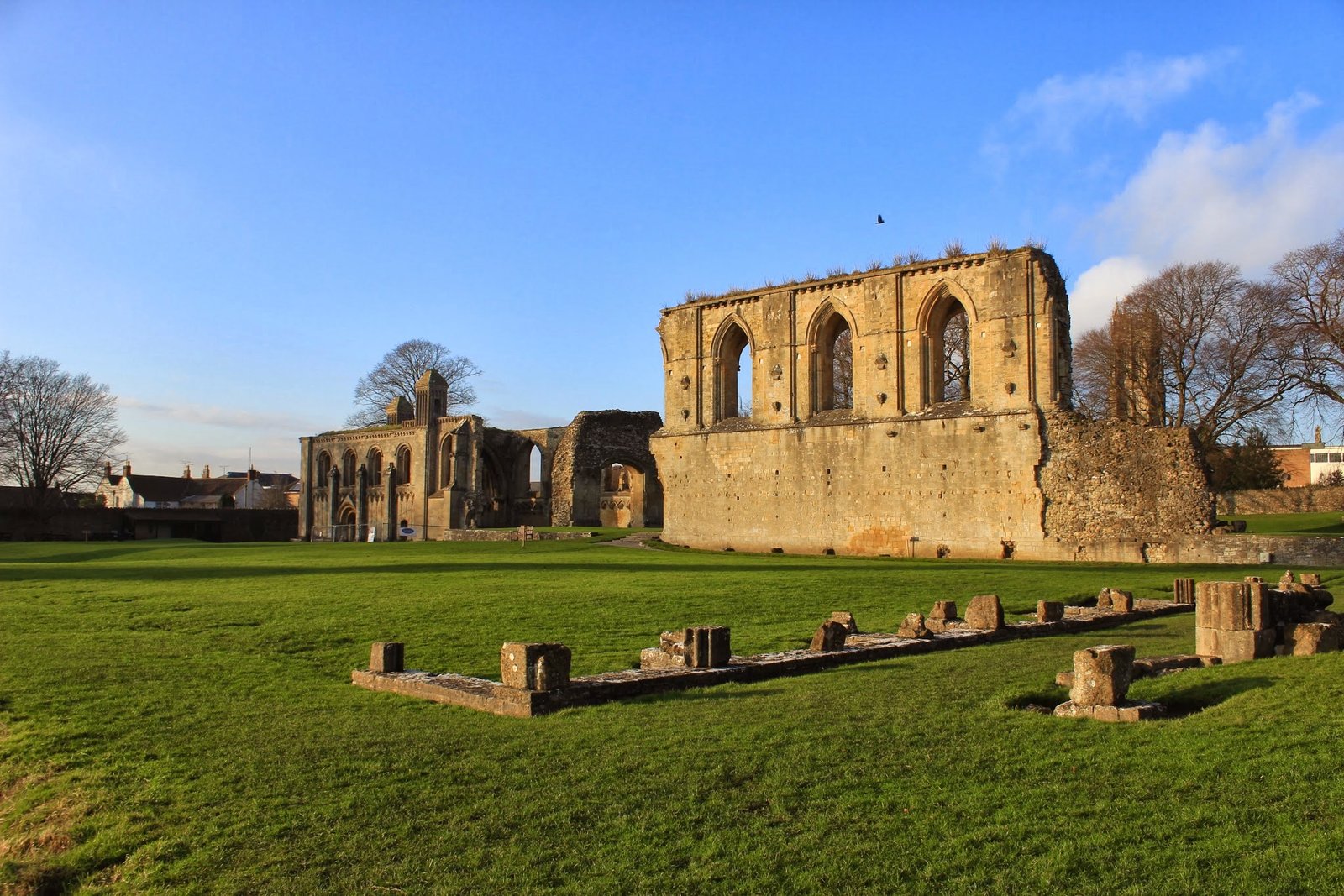 The ruined stone arches of Glastonbury Abbey standing against a green English landscape